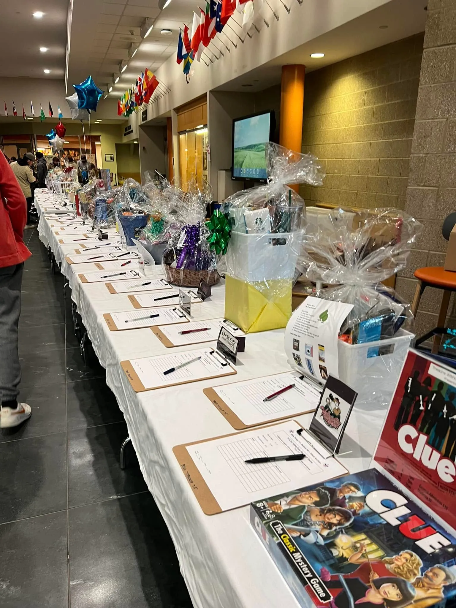 A long silent auction table lined with gift baskets and bid sheets