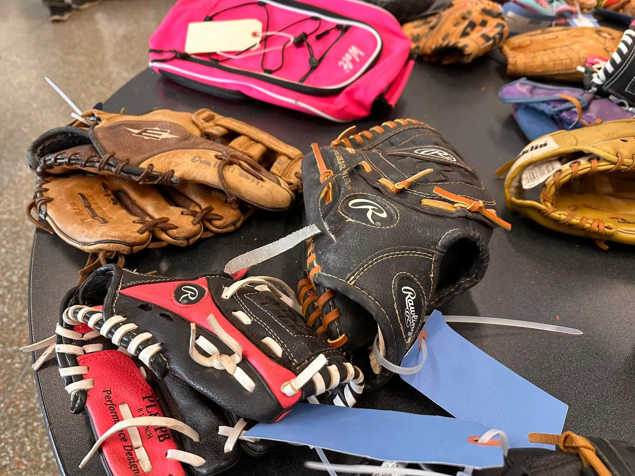 Baseball and softball gloves piled on a sale table