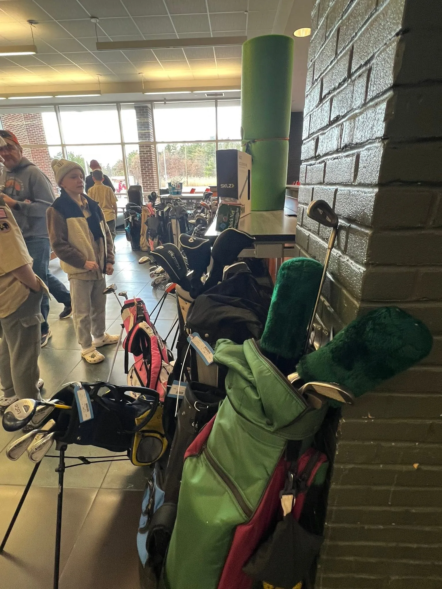 Golf bags and clubs lined up along a wall