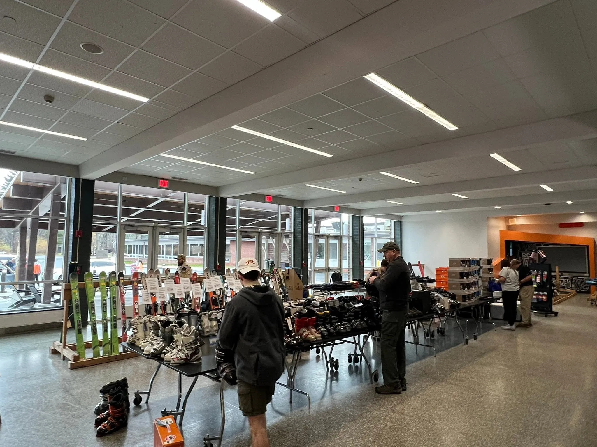 Shoppers browsing tables of ski boots and skis